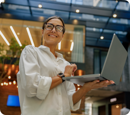 gerente-de-vendas-sorridente-trabalhando-em-laptop-enquanto-esta-de-pe-em-um-fundo-de-coworking-moderno